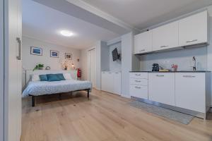 a bedroom with a bed and a kitchen with white cabinets at Bellano Holidays - Casa Ortensia in Bellano