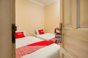 two beds in a small room with red pillows at Hotel O 211 in Parapat