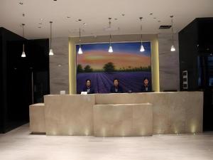 three men standing behind a counter in a room with a painting at Lavande Hotel Changsha High-Speed Railway Station Shumuling Metro Station in Changsha