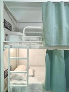 two bunk beds in a dorm room with blue curtains at Port Douglas Backpackers in Port Douglas +22 photos