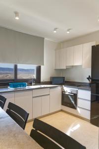 a kitchen with white cabinets and a table and chairs at VESTA - El Gouna Residence in Hurghada