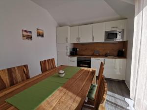 a kitchen with a wooden table with chairs and a microwave at Ferienwohnung in Zingst Müggenburg, hochwertig und ruhig urlauben in Müggenburg