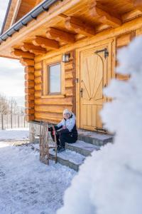 Eine Frau sitzt auf der Treppe vor einer Blockhütte in der Unterkunft Złoty Groń log houses & apartments in Istebna
