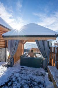 Ein Mann sitzt in einer Badewanne im Schnee in der Unterkunft Złoty Groń log houses & apartments in Istebna