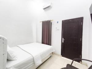 a bedroom with a bed and a black door at HAJIMENA INN Syariah By Hans Management in Hajimana