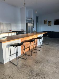 a kitchen with a large wooden counter with stools at Birdys Retreat in Rarotonga