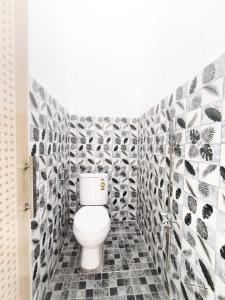 a bathroom with a toilet in a black and white tiles at HAJIMENA INN Syariah By Hans Management in Hajimana