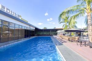 クラークにあるOlle Hotel Clark City powered by Cocotelの建物の隣にあるテーブルとパラソルのあるプール +12枚の写真