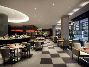 a restaurant with tables and chairs and a checkerboard floor at Pullman Miri Waterfront in Miri