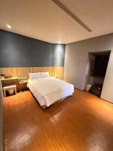 Schlafzimmer mit einem weißen Bett und Holzboden in der Unterkunft The Prince Hotel in Tainan
