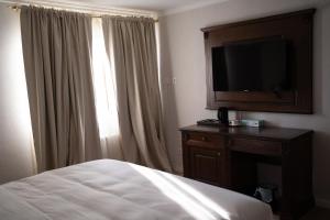 a hotel room with a bed and a flat screen tv at John Bull House in Buzău