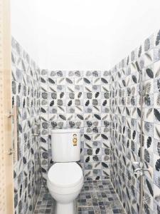a bathroom with a toilet and a tiled wall at HAJIMENA INN Syariah By Hans Management in Hajimana