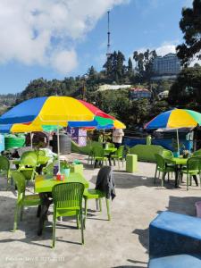 een groep tafels en stoelen met parasols bij P Square Resto Cafe n Stay in Darjeeling