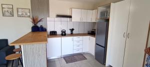 una cucina con mobili bianchi e un frigorifero nero di Bella Vanti Views Self Catering a West Point Altre 5 foto