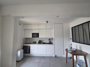 eine Küche mit weißen Schränken und einem Waschbecken und einem Tisch in der Unterkunft Joli 4 pièces - Terrasse vue mer - Parking - FC in Saint-Laurent-du-Var