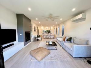 The Ebb Luxury Retreat - Just steps to the beach! في أوشن غروف: غرفة معيشة مع أريكة وتلفزيون بشاشة مسطحة