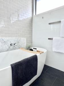 The Ebb Luxury Retreat - Just steps to the beach! في أوشن غروف: حمام أبيض مع حوض استحمام ومناشف