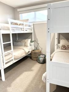 The Ebb Luxury Retreat - Just steps to the beach! في أوشن غروف: سريرين بيض بطابقين في غرفة مع نافذة