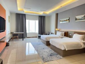 a hotel room with two beds and a flat screen tv at Season Inn Hotel_Al Hail in Seeb