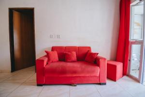a red couch with red pillows in a room at Doce Lar São Francisco in Cabo de Santo Agostinho