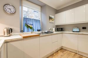 uma cozinha com armários brancos e um relógio na parede em Market Street No 28a - St Andrews em St Andrews