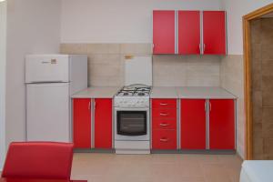 a red kitchen with white appliances and a red chair at Andjelka B4-Blue in Mali Lošinj