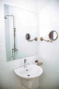 Un baño blanco con lavabo y espejo. en The Hub Train House Apartments, en Zanzíbar