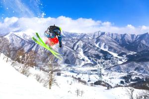 Eine Person, die auf Skiern im Schnee in die Luft springt in der Unterkunft Naeba Prince Hotel in Yuzawa