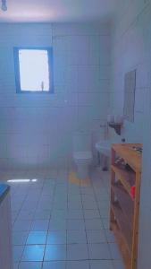 Un baño con inodoro, lavabo y ventana. en HIGSAM apartment, en Diani Beach