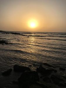 un tramonto sulla spiaggia con oceano e rocce di HIGSAM apartment a Diani Beach