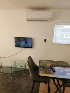 a living room with a table and a tv on a wall at Guest House Tokoroa in Tokoroa
