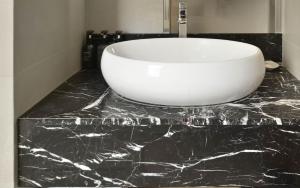 a bathroom with a white sink on a black counter at Eco Tree Hotel Sheung Wan in Hong Kong