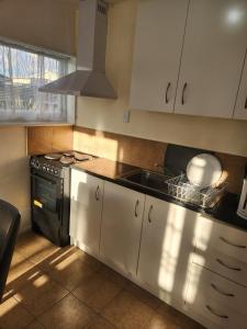 a kitchen with white cabinets and a sink and a stove at Guest House Tokoroa in Tokoroa