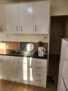 a kitchen with white cabinets and a sink at Guest House Tokoroa in Tokoroa