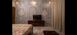 Una habitación con un televisor, una cama y una pared. en PichwaiHouse, en Jaipur