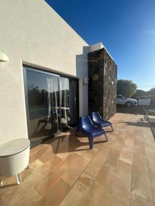 a patio with two blue chairs and a large window at Villa Groovy in Lajares