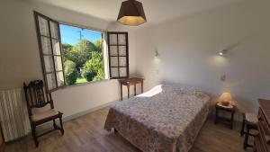 a bedroom with a bed and a chair and a window at Verte Rive – Maison climatisée en bord de Dordogne in Cénac-et-Saint-Julien