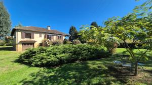 a house with a tree and a bench in the yard at Verte Rive – Maison climatisée en bord de Dordogne in Cénac-et-Saint-Julien