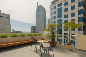 eine Terrasse mit Tisch und Stühlen auf einem Balkon in der Unterkunft White Lotus Hotel Saigon in Ho-Chi-Minh-Stadt
