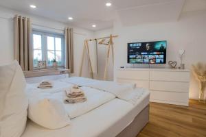 a white bedroom with a large bed and a television at Alpenloft mit Garten & BBQ am Chiemsee by Dollop Living in Bernau am Chiemsee