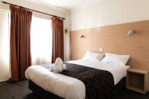 Una habitación de hotel con una cama con un animal de peluche encima. en Sphinx Hotel, en Hamlyn Heights