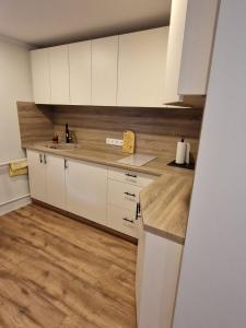 a kitchen with white cabinets and a wooden floor at Brīvdienu māja Vecdaugavā in Rīga