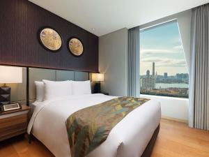 首尔Grand Mercure Ambassador Hotel and Residences Seoul Yongsan的一间卧室，配有一张大床和一扇大窗户。