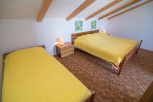 two beds in a room with yellow sheets at Andjelka B4-Blue in Mali Lošinj