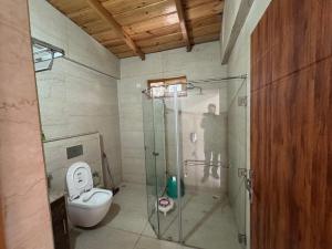 a bathroom with a toilet and a glass shower stall at Shail by Shubhs in Bhowāli +109 photos