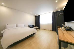 una camera da letto con un grande letto bianco e una scrivania di Mokpo Ayana Hotel & Poolvilla a Mokpo Altre 52 foto
