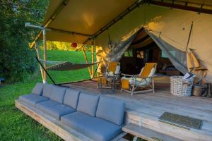 Kanimbia Luxury Glamping في Obi Obi: أريكة في خيمة مع طاولة وكراسي