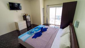 Schlafzimmer mit einem Bett mit blauer Bettwäsche und einem TV in der Unterkunft Kata Lina guesthouse in Kata Beach