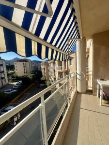 einen Balkon mit einem blauen und weißen Schirm in der Unterkunft Apartment 2 steps from Ile-Rousse Beach in LʼÎle-Rousse