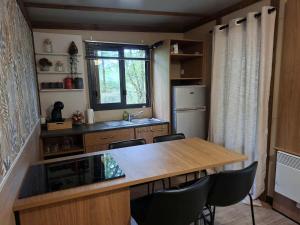 una cucina con tavolo, sedie e frigorifero di Chalet au bois tranquille a Saint-André-de-Double